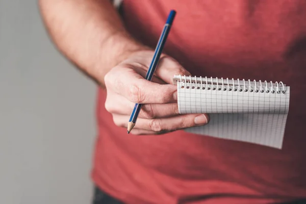 Sujetando un pequeño bloc de notas en espiral y un lápiz en una mano — Foto de Stock