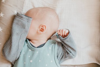 uyuyan bebek kollarıyla gözlerini kapatıyor.