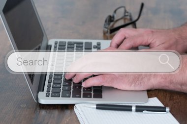 Arama motoru arama kutusu kaplamalı ahşap masada dizüstü bilgisayar kullanan kişi