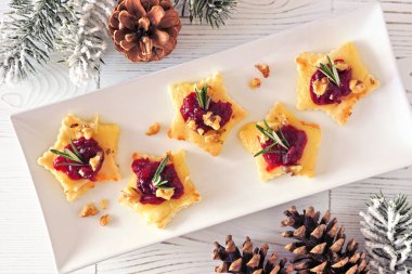 Noel yıldızı, kızılcık ve fırınlanmış peynirle aperatifleri şekillendirdi. Beyaz ahşap bir arka plana karşı üst görünüm tablo sahnesi.