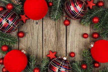 Noel çerçevesi, ağaç dallarıyla kırmızı ve parlak ekoseli süsler. Kopya alanı olan bir ahşap arka planda genel görünüm.
