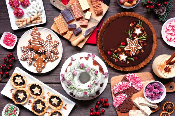 各种各样的圣诞假期甜点和糖果 在一个木制背景上俯瞰桌子上的场景 包扎蛋糕 巧克力派 软糖和蛋酒 — 图库照片