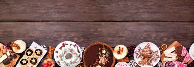 Yılbaşı tatlıları ve tatlıları çeşitleri. Ahşap kaplama arkaplanı üzerinden alt sınır görünüyor. Pasta, çikolatalı turta, kıymalı tart, kurabiye ve eggnog..