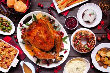 Geleneksel Noel hindisi yemeği. Koyu renk ahşap arka planda en üstteki masa sahnesi. Hindi, patates, sos, meyveli pasta ve erikli puding..