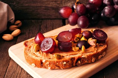 Kahvaltıda fındık ezmeli, üzümlü ve fıstıklı kızarmış ekmek. Koyu renk ahşap arka planda kapat..