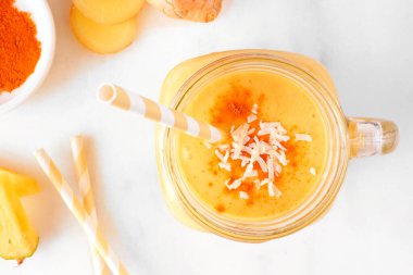 Mason kavanozunda zerdeçal ve zencefilli buzlu içecek. Beyaz mermer bir arka planı var. Sağlıklı bağışıklık güçlendirici, kilo kaybı, iltihap önleyici.