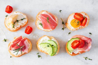 Çeşitli malzemelerle krem peynirli crostini d 'oeuvres çeşitleri. Beyaz mermer arka planda yukarıda. Parti yemeği konsepti.