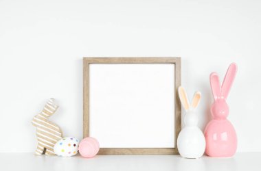 Paskalya yumurtası ve beyaz bir rafta tavşan dekoru ile ahşap çerçeve yap. Beyaz bir duvara karşı kare çerçeve. Boşluğu kopyala.