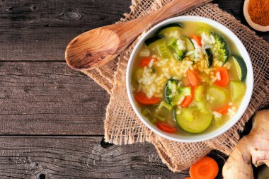 Zerdeçal ve zencefilli sağlıklı sebze çorbası. Koyu renk ahşap bir arka planda üst görünüm masası sahnesi.