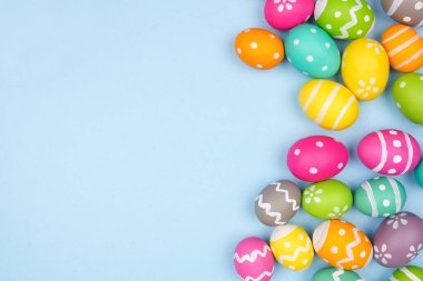 Renkli Paskalya yumurtası kenarı pastel mavi kağıt arka planda. Boşluğu kopyala.