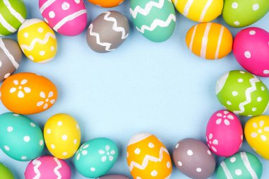 Renkli Paskalya Yumurtası çerçevesi pastel mavi kağıt arka planda. Boşluğu kopyala.