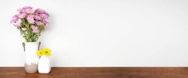 Rafta ev dekorasyonu. Bahar çiçekli vazolar. Beyaz bir duvara karşı ahşap bir raf. Kopyalama alanı olan pankart.