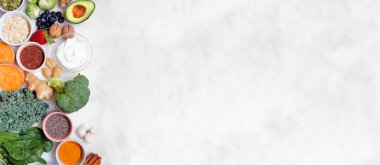 Sağlıklı besin maddeleri. Beyaz afiş arkaplanındaki yan sınır manzarası. Uzayı kopyala Yeşil sebzeler, böğürtlenler, tam tahıllar, tohumlar, baharatlar ve besleyici maddelerle süper gıda konsepti.