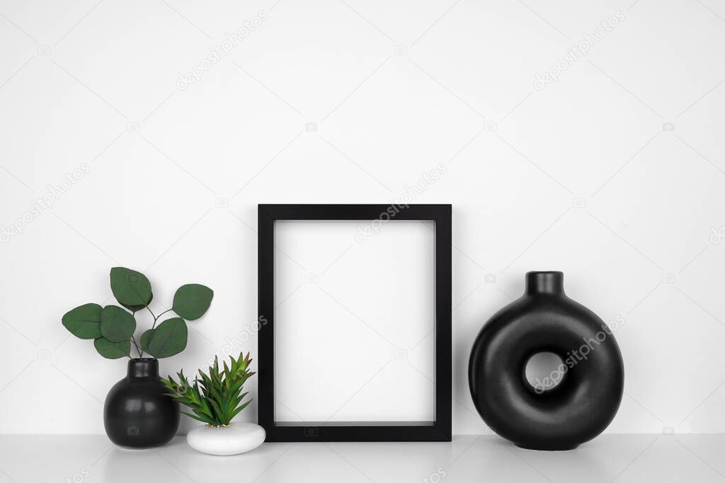 Mock up black frame with modern black. White shelf against a white wall. Copy space.