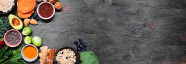 Sağlıklı besin maddeleri. Pankart arka planında tepe köşesi sınırı var. Uzayı kopyala Yeşil sebzeler, böğürtlenler, tam tahıllar, tohumlar, baharatlar ve besleyici maddelerle süper gıda konsepti.