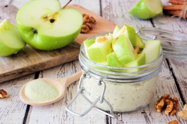 Bir gecede kibritli yulaf ve kırsal beyaz ahşap arka planda bir kavanozda yeşil elma.