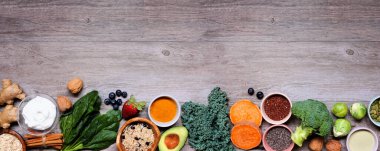 Sağlıklı gıda malzemeleri seti. Ahşap bir arka planda üst sınır görünüyor. Uzayı kopyala Yeşil sebzeler, böğürtlenler, tam tahıllar, tohumlar, baharatlar ve besleyici maddelerle süper gıda konsepti.