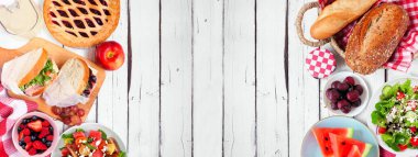 Yaz pikniği yiyecekleri çifte sınır. Çeşitli soğuk salatalar, sandviçler, meyve ve ikramlar. Beyaz ahşap bir arkaplanda manzaranın üstünde. Boşluğu kopyala.