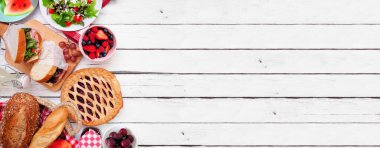 Yaz pikniği yan sınırı. Çeşitli soğuk salatalar, sandviçler, meyveler ve ikramlar. Beyaz ahşap bir arkaplanda manzaranın üstünde. Boşluğu kopyala.