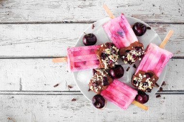 Yaz çikolatası ve fındıklı vişneli buzlu dondurmayı tabağa koy. Beyaz ahşap arka planda manzaranın üstünde.