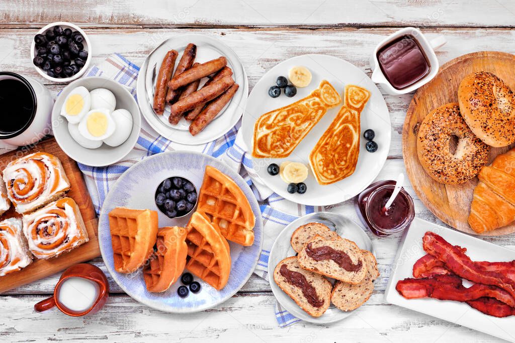 Fathers Day breakfast table scene. Overhead view on a white wood background. Tie pancakes, mustache toast and a selection of dad themed food.