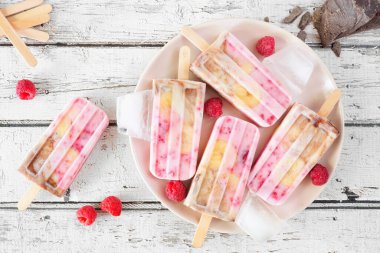 Ev yapımı ahududu, çikolata, muzlu yoğurt. Kırsal beyaz ahşap arka planda üst görünüm tablo sahnesi.