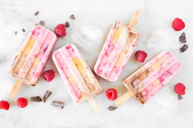 Ev yapımı ahududu, çikolata, muzlu yoğurtlu dondurma. Üst görünüm beyaz mermer arka planda dağınık.