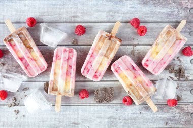 Ev yapımı ahududu, çikolata, muzlu yoğurt. Kırsal bir ahşap zemine serpiştirilmiş genel manzara.