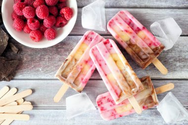 Ev yapımı ahududu, çikolata, muz, yoğurtlu dondurma. Kırsal bir ahşap arka planda yukarıdaki masa sahnesi.