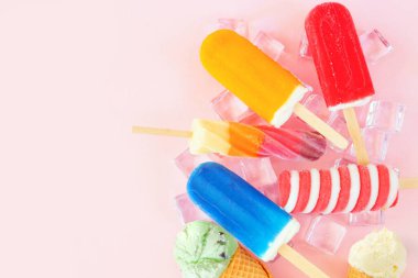 Renkli yaz buzlu dondurmaları ve dondurmalar. Pembe arka planda serpiştirilmiş yukarıdaki manzara. Boşluğu kopyala.