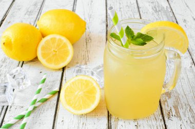 Kavanoz bardakta buzlu yeşil limonata. Beyaz ahşap arka plana karşı masa sahnesi.