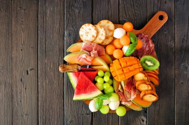 Yazın meyve temalı şarküteri tahtası koyu renk ahşap arka plana karşı. Meyve, peynir ve meze. Üst görünüm.