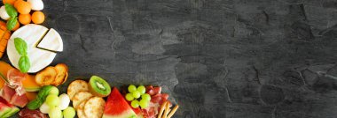 Yaz meyveleri temalı şarküteri köşe sınırı koyu bir arka plana karşı. Meyve, peynir ve meze. Boşluğu kopyala.