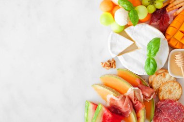 Yaz meyveleri temalı şarküteri köşe sınırı beyaz mermer arka planda. Meyve, peynir ve meze çeşitleri. Boşluğu kopyala.