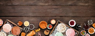 Yaz dondurması, çeşitli tatlar ve tatlı malzemelerle birlikte. Koyu ahşap arkaplanda üst görünüm sınırı.