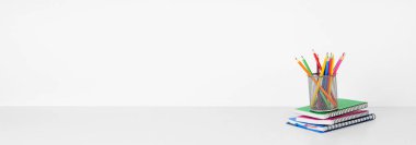 Okul malzemeleri beyaz bir rafta, arka planda beyaz bir duvar var. Okul konseptine geri dönelim. Boşluğu kopyala.