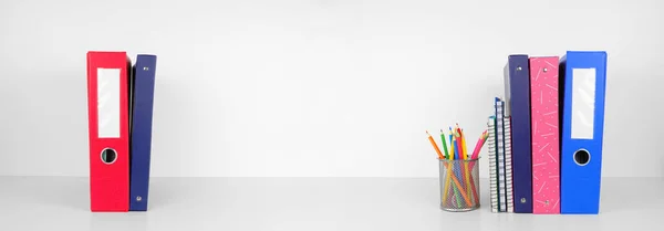 School supplies and binders on a white shelf against a white wall banner background. Back to school concept. Copy space.