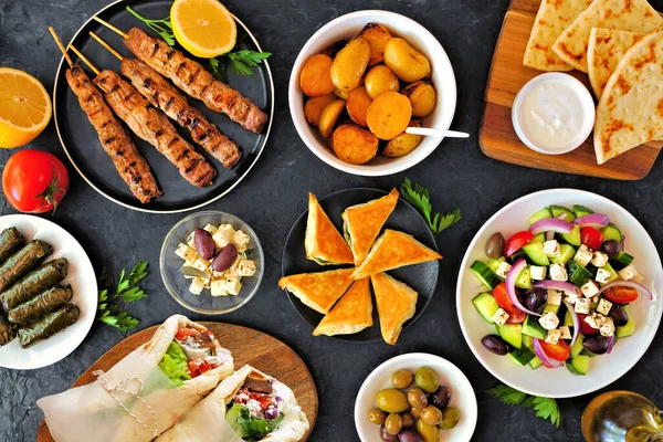 Greek food double border, top view on a dark banner background. Souvlaki, gyros wraps, salad, spanakopita, dolmades, pita and lemon potatoes. Copy space.