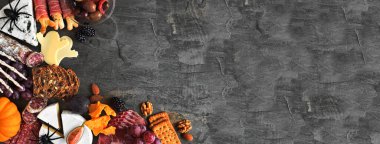 Cadılar Bayramı temalı şarküteri köşe sınırı koyu taştan bir afişe karşı. Peynir ve meze çeşitleri. Boşluğu kopyala.