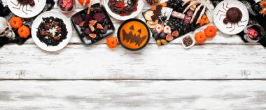 Cadılar Bayramı partisi beyaz ahşap pankartın en üst sınırında. Genel bakış. Siyah risotto ve makarna, şarküteri tahtası, balkabağı çorbası, örümcek pastası ve elma kafatası şarabı..