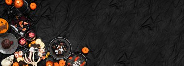 Cadılar Bayramı partisinin köşesinde koyu siyah bir afiş var. Genel bakış. Şarküteri tahtası, siyah risotto ve makarna, örümcek pastası, balkabağı çorbası ve elma kafatası şarabı.