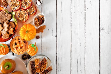 Sonbahar tatlıları yan sınırda. Bir grup tatlı güz ikramının olduğu masa sahnesi. Beyaz ahşap arka planda manzaranın üstünde. Boşluğu kopyala.