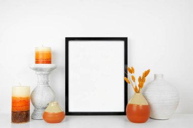 Siyah çerçeveyi sonbahar dekoruyla beyaz bir rafta düzenle. Sonbahar konsepti. Beyaz bir duvara dayalı portre çerçevesi.