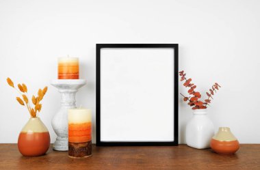 Düşen dallar ve ahşap bir rafta dekoru olan siyah bir çerçeve yap. Sonbahar konsepti. Beyaz bir duvara dayalı portre çerçevesi.