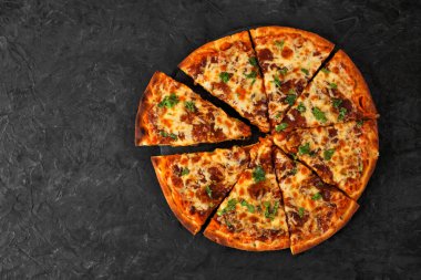 Balkabağı soslu sonbahar pizzası, gouda ve karamelli soğan. Dilimlenmiş. Koyu bir arkaplanda genel görünüm.