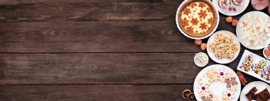 Noel kurabiyeleri ve tatlılar yan sınırda. Koyu renk ahşap afiş arkaplanda yukarıdan görünüyor. Eggnog turtası, çeşitli kurabiyeler, meyveli pasta, kekler ve çikolatalı eggnog. Boşluğu kopyala.