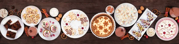 Noel kurabiyeleri ve tatlı masası sahnesi. Koyu ahşap arka planda üst manzara. Eggnog turtası, çeşitli kurabiyeler, meyveli pasta, kekler ve çikolatalı eggnog..