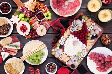 Karanlık bir ahşap arka planda Noel şarküteri masası sahnesi. Genel bakış. Çeşit çeşit peynir, meyve ve et mezeleri..