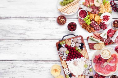 Noel tatili şarküteri yan sınırında beyaz ahşap bir arka planda. Yukarıdan aşağıya doğru. Çeşit çeşit peynir, meyve ve et mezeleri. Boşluğu kopyala.