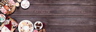 Noel kurabiyeleri ve tatlıların köşesi. Koyu ahşap bir arkaplanda manzaranın üstünde. Noel Baba otlatma tahtası, kurabiye tabakları ve tatlı tabaklar. Boşluğu kopyala.